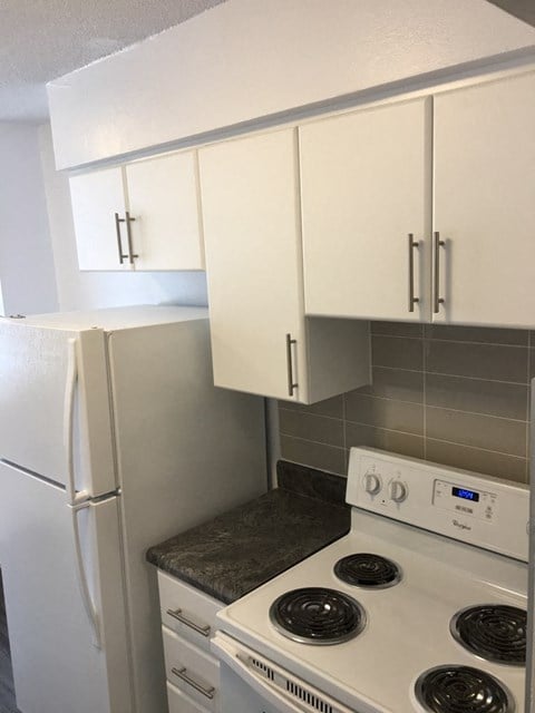 a kitchen with white cabinets and a stove and a refrigerator